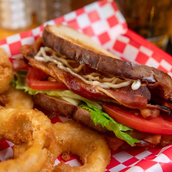 Sooner Daiquiri's BLT sandwich with crispy bacon, fresh lettuce, and tomato, served with onion rings.