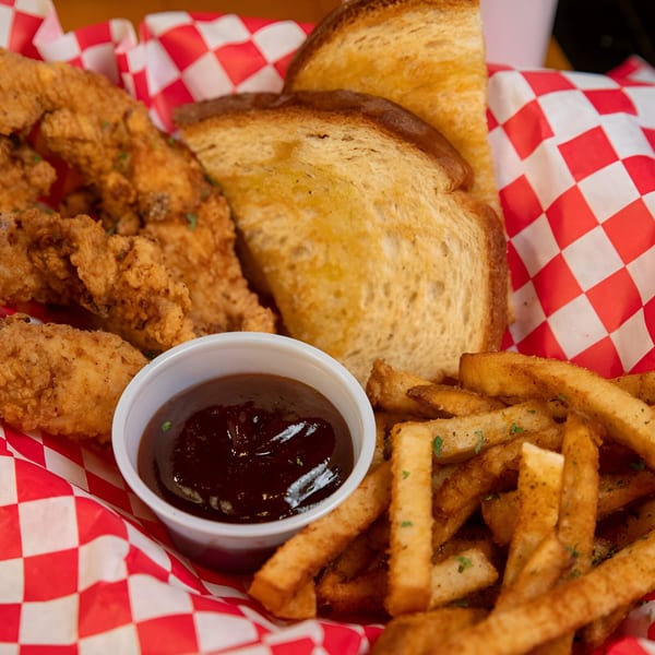 Sooner Daiquiri's chicken tenders, fries, Texas toast, and barbecue sauce in a red checkered basket.